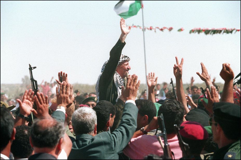 On July 1, 1994, Arafat waves to a crowd of cheering Palestinians as he crosses the border into Gaza for the first time in 27 years.