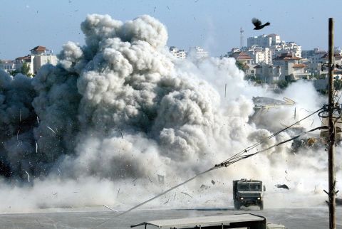 A large explosion rocks Arafat's headquarters in Ramallah moments after Israeli troops blew up a building on September 20, 2002. It was the start of a 10-day siege.