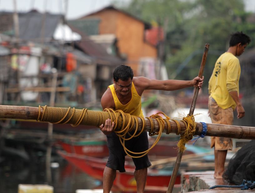 A fisherman lifts a post to reinforce his home at a coastal village in Las Pinas on November 8.