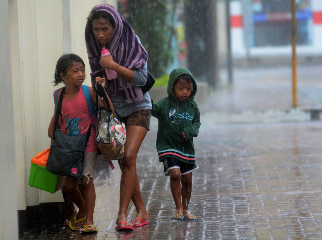 A woman and her children head for an evacuation center November 8 amid strong winds in Cebu City, Philippines.