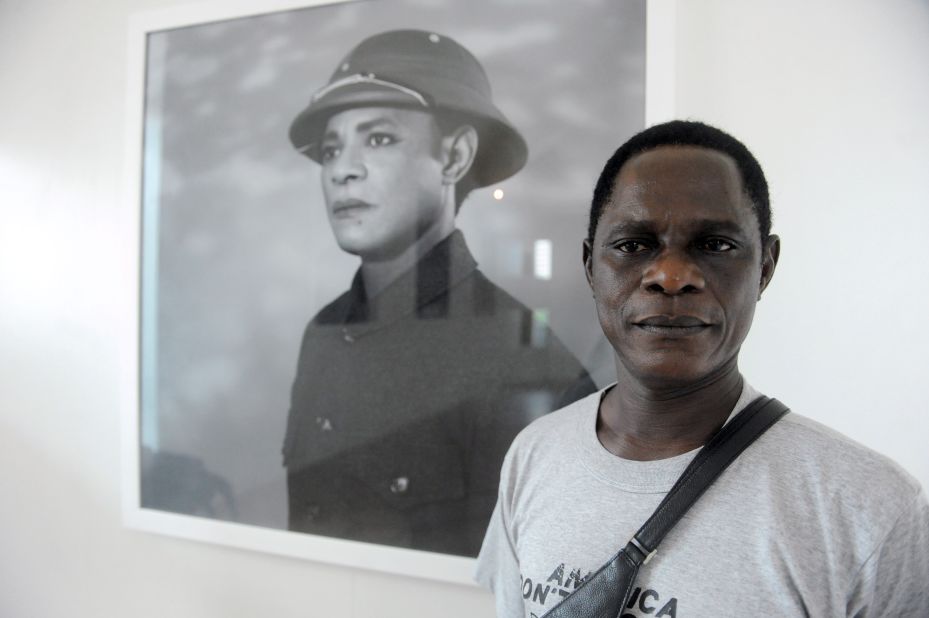 Samuel Fosso poses next to his self portrait, in which he transforms into Chinese leader Mao Zedong for his latest photographic series titled "The Emperor of Africa," premiered at this year's LagosPhoto Festival. 