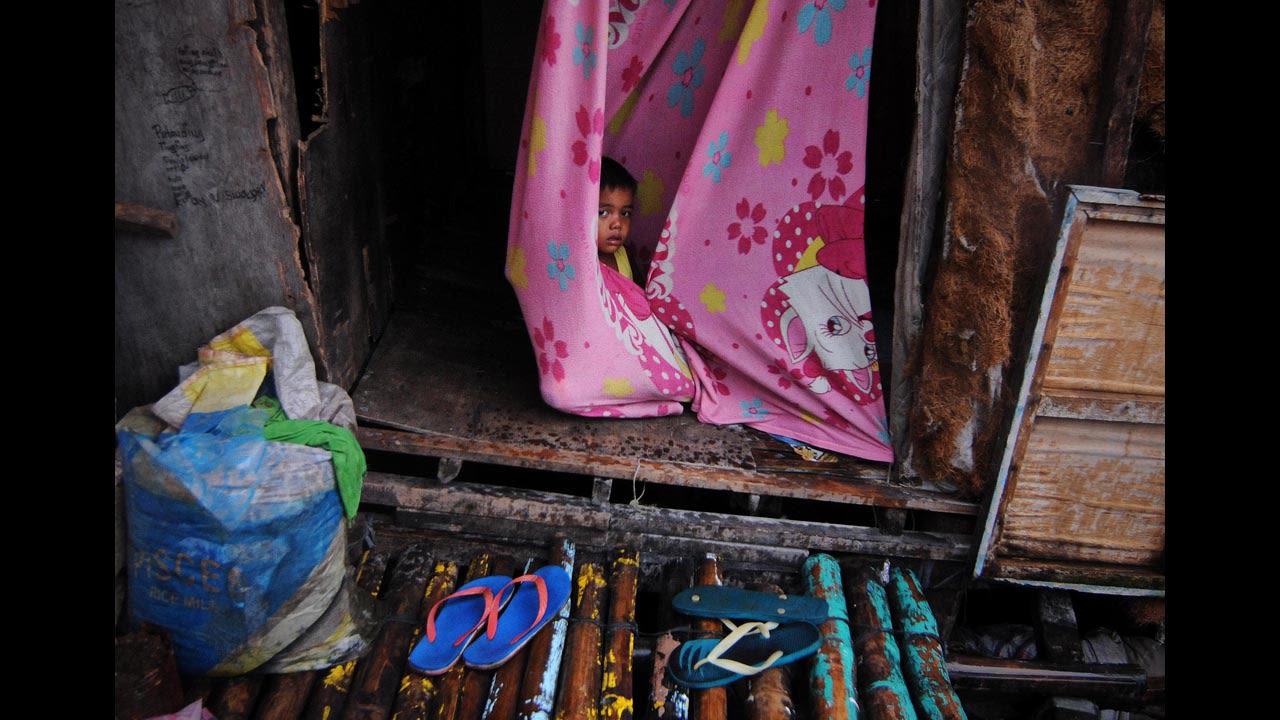 A child wraps himself in a blanket inside a makeshift house along a Bacoor fishing village.