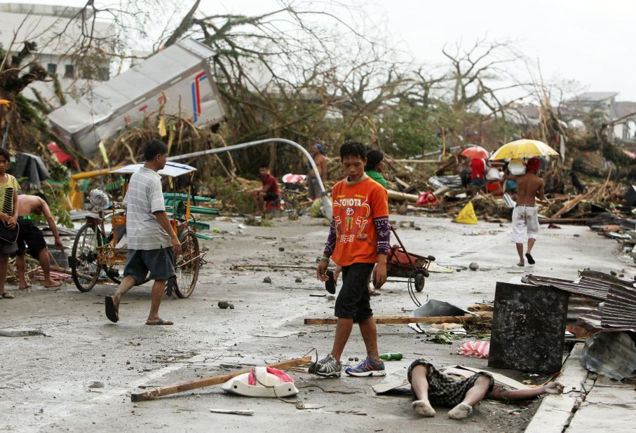 People walk past a victim left on the side of a road in Tacloban.