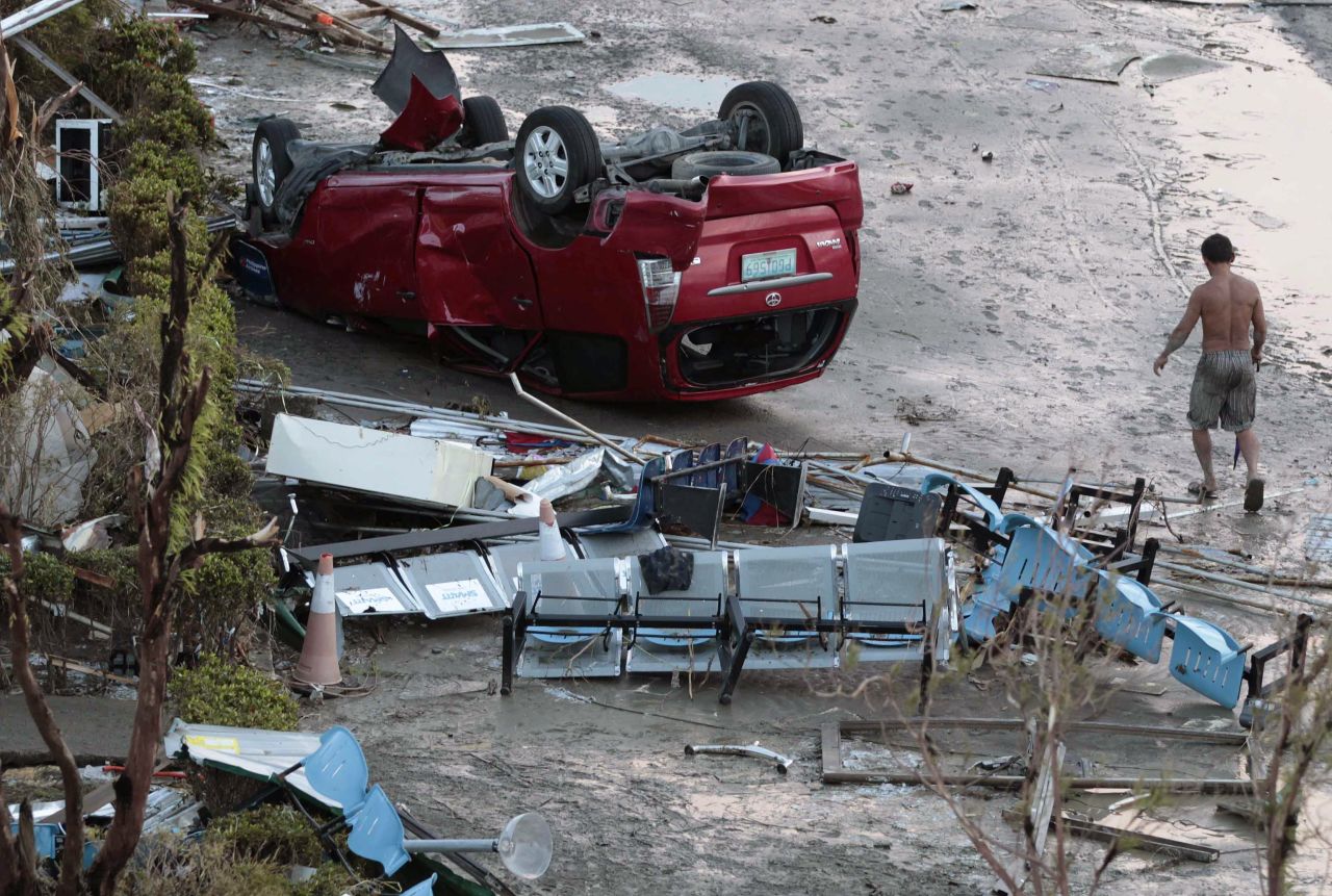 A resident passes an overturned car in Tacloban on November 9.