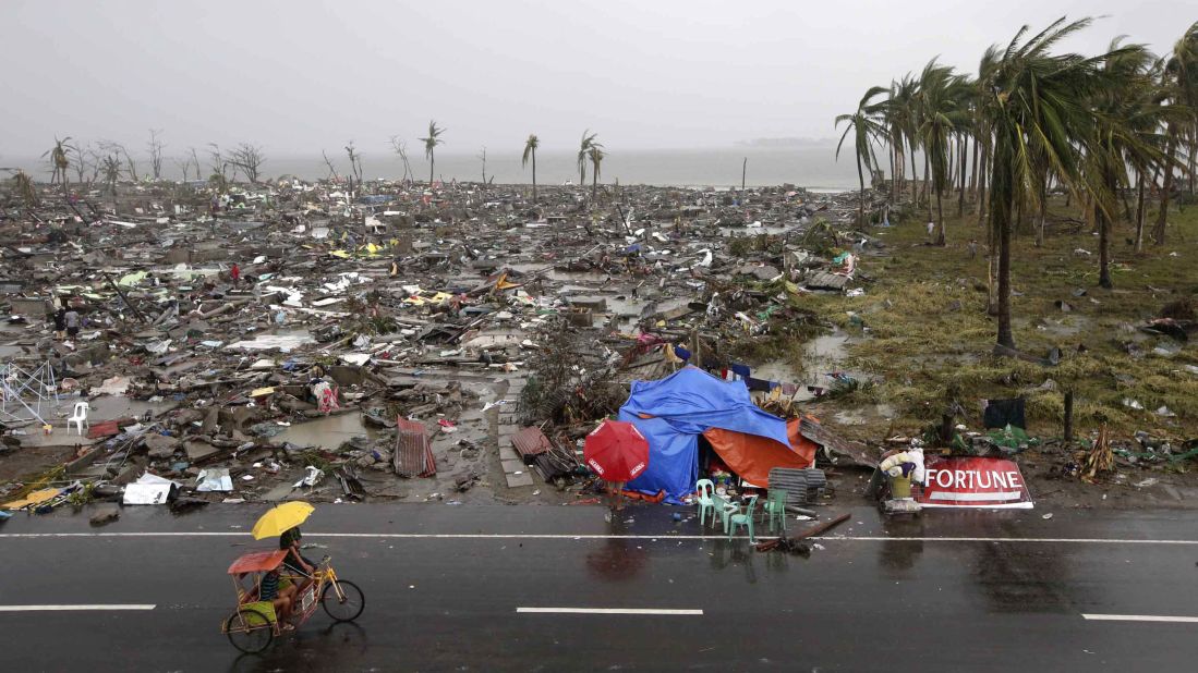People ride past destruction in Tacloban on Sunday, November 10.