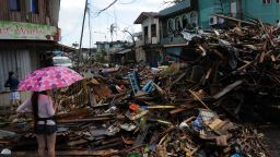 A resident stands amongst a pile of debris washed inland along a road in Tacloban, Leyte province, central Philippines on November 10, 2013, three days after devastating Typhoon Haiyan hit the city on November 8.