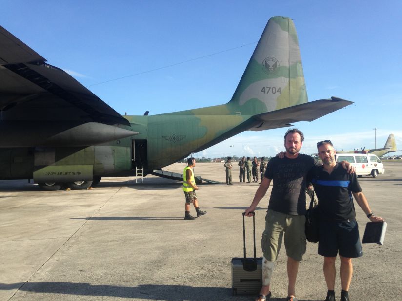 Relieved storm chasers Mark Thomas and Josh Morgerman near the C-310 they caught out of Tacloban after hearing a tip-off about military flights out of the typhoon-hit Filipino city.