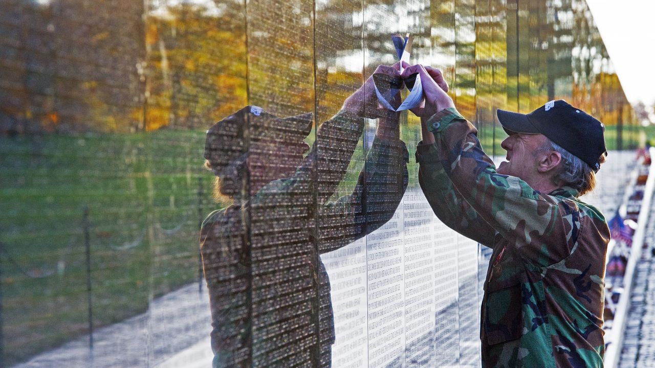 A man traces the name of a fallen soldier off the wall of Vietnam War Memorial.