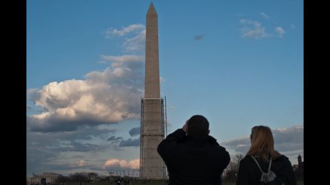 A tourist takes a photo of the Washington Monument — half-covered in scaffolding — in March 2013.