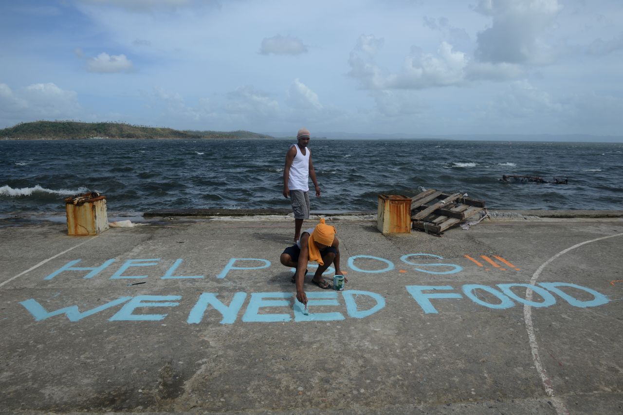 A man seeking aid paints a message on a basketball court November 11 in Anibong, Philippines.