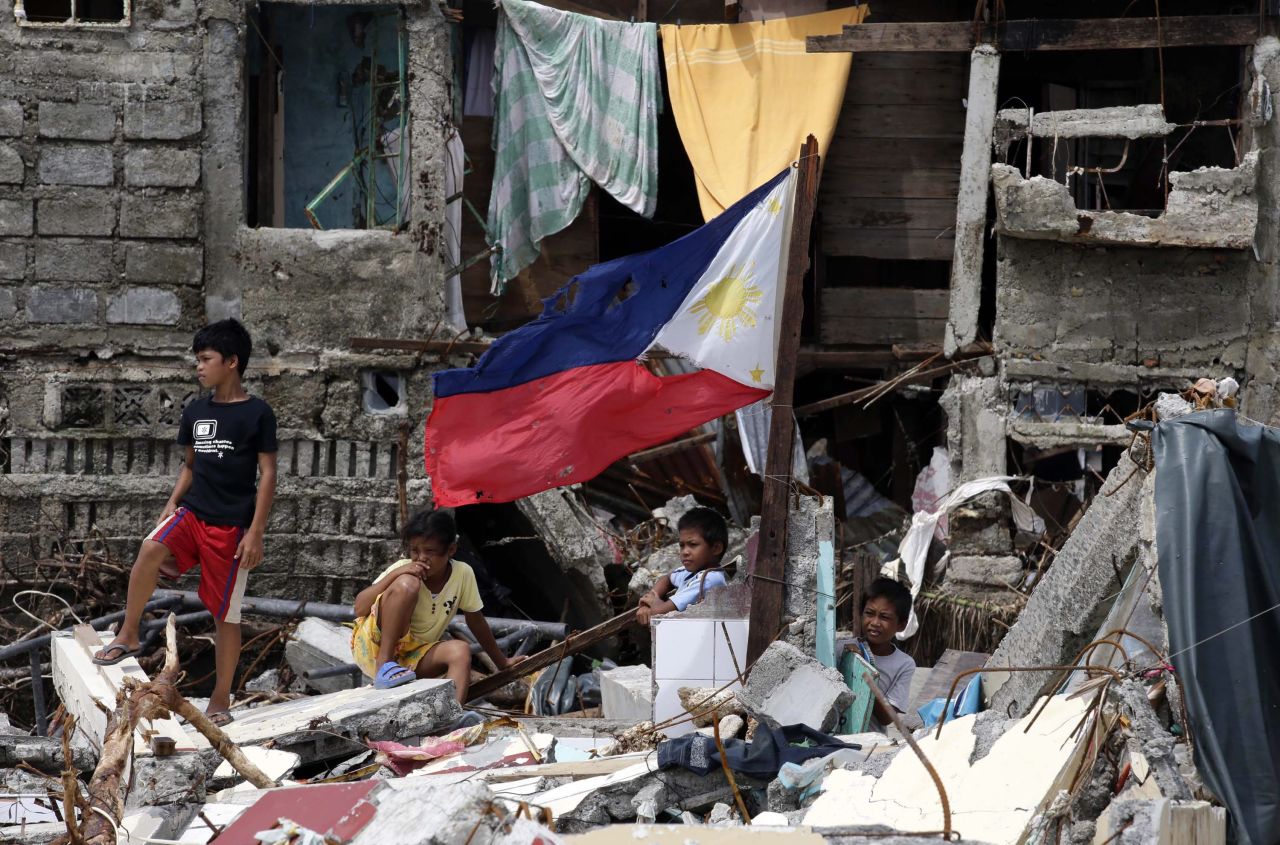 Niños descansan entre los escombros en Hernani, Filipinas, otra ciudad devastada por la tormenta, el lunes 11 de noviembre.