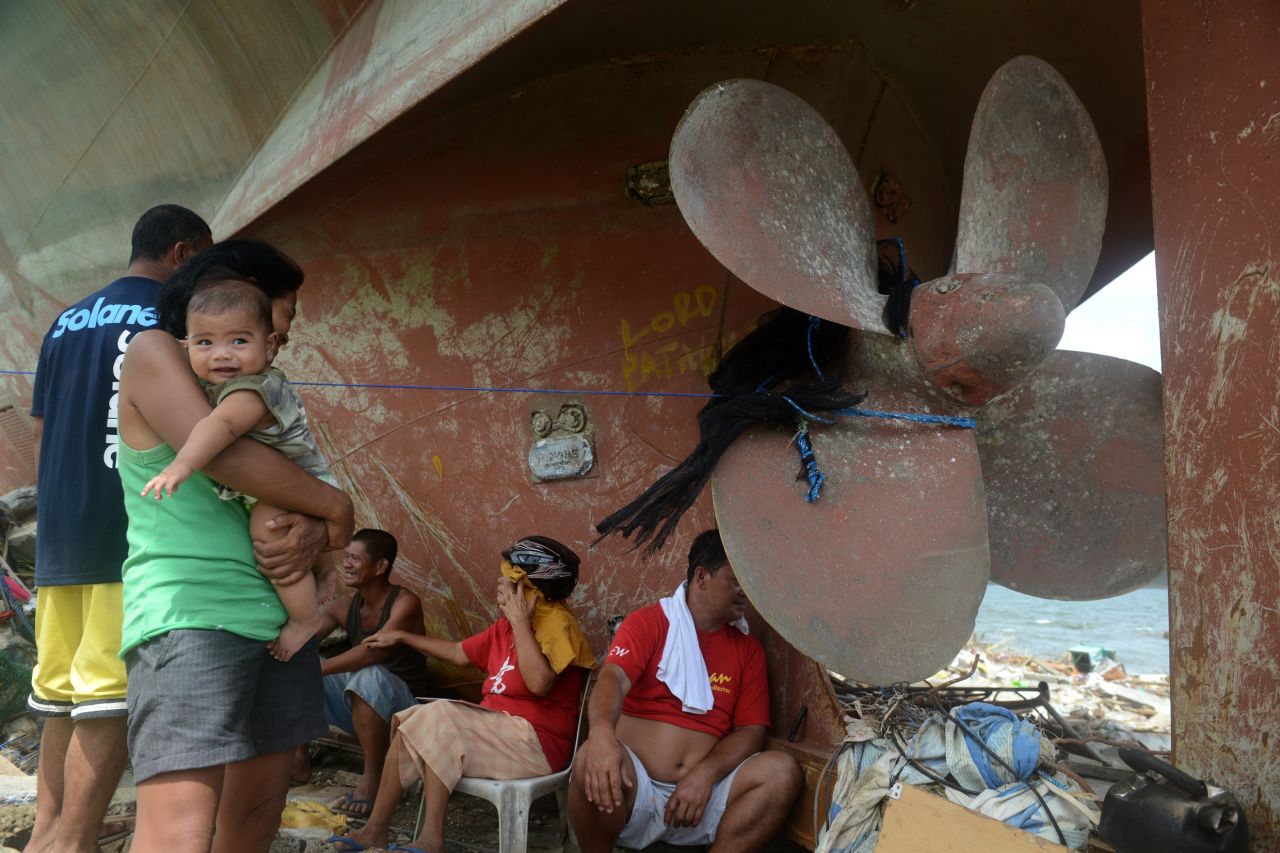 Los residentes de Anibong, Filipinas, descansan el 11 de noviembre cerca de una hélice de barco que llegó a la orilla durante el tifón Haiyan.