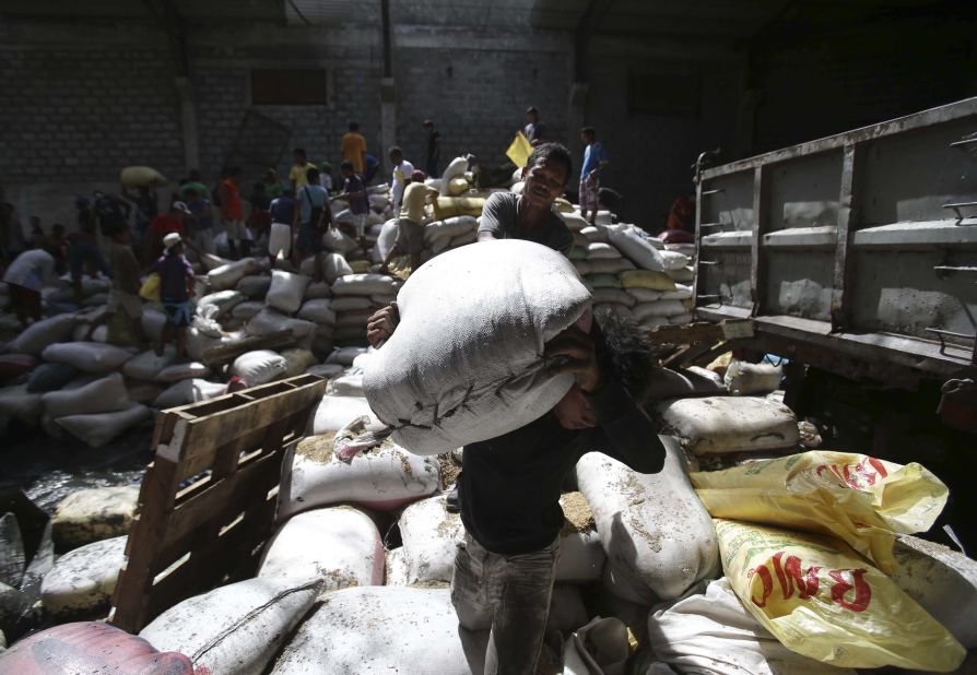 Residents carry bags of rice from a Tacloban warehouse that they stormed November 11 because of a food shortage.