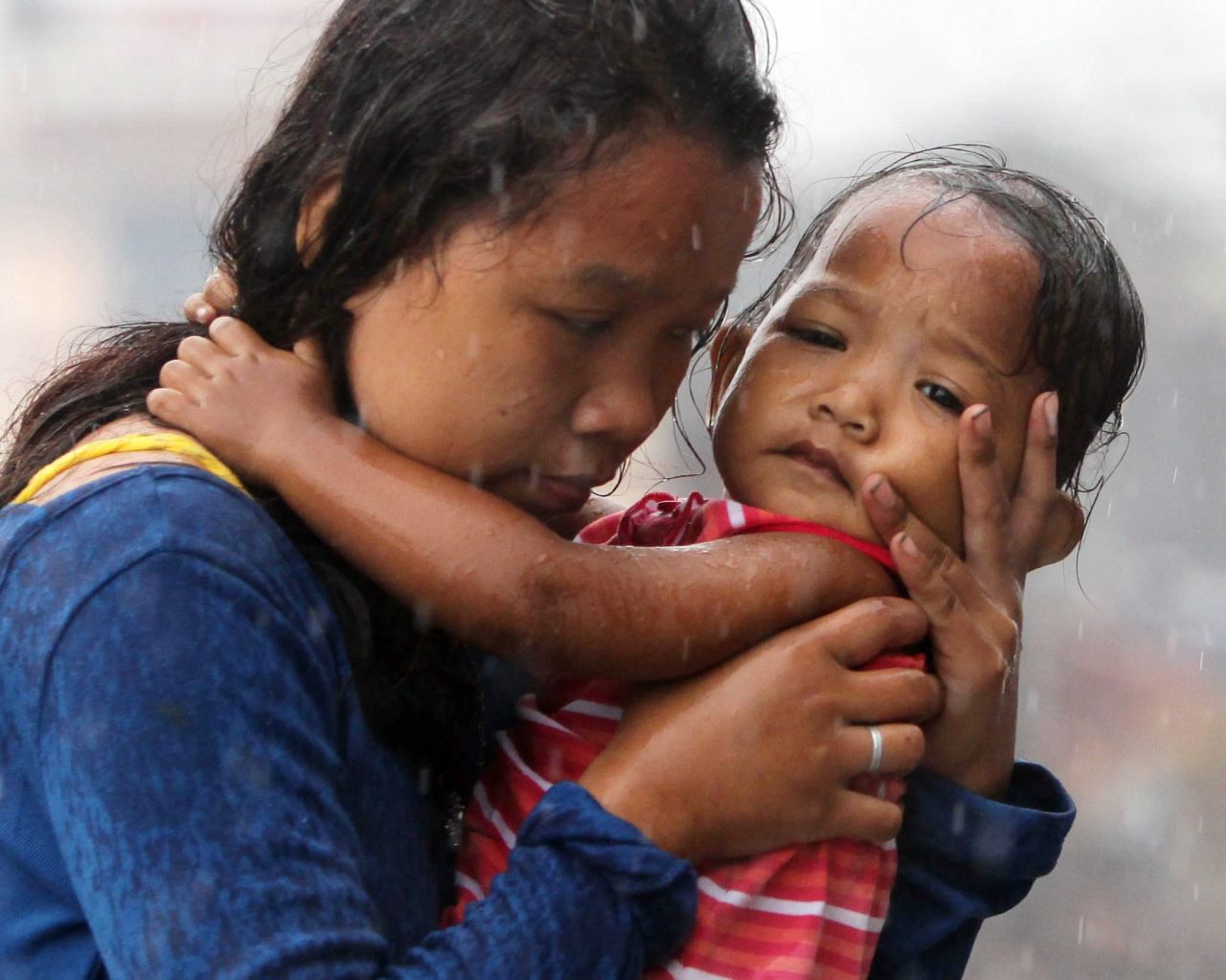 Una mujer sostiene a un bebé durante un aguacero el martes 12 de noviembre, en la devastada ciudad de Tacloban, Filipinas. Haiyan, una de las tormentas más fuertes de la historia, arrasó las Filipinas y mató a cientos de personas.