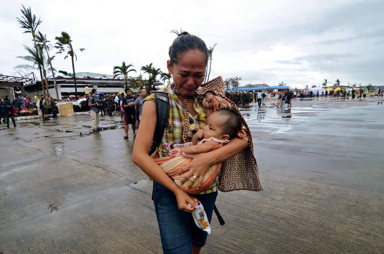 Una mujer llora mientras lleva a un niño a un avión militar en Leyte, el 12 de noviembre.