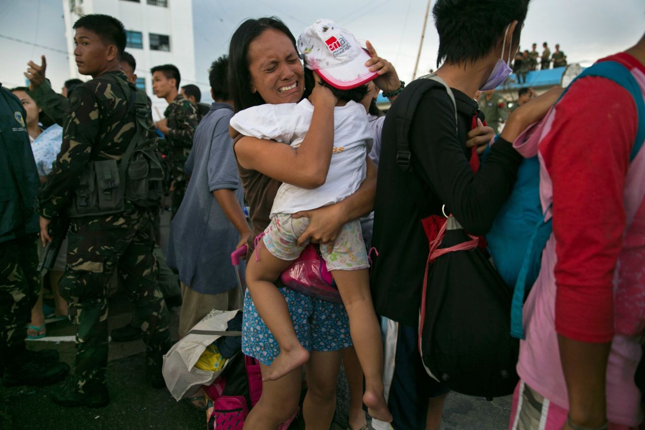 Una mujer carga a un niño en medio del llanto el 12 de noviembre mientras los sobrevivientes esperan para embarcar en un avión en Tacloban.