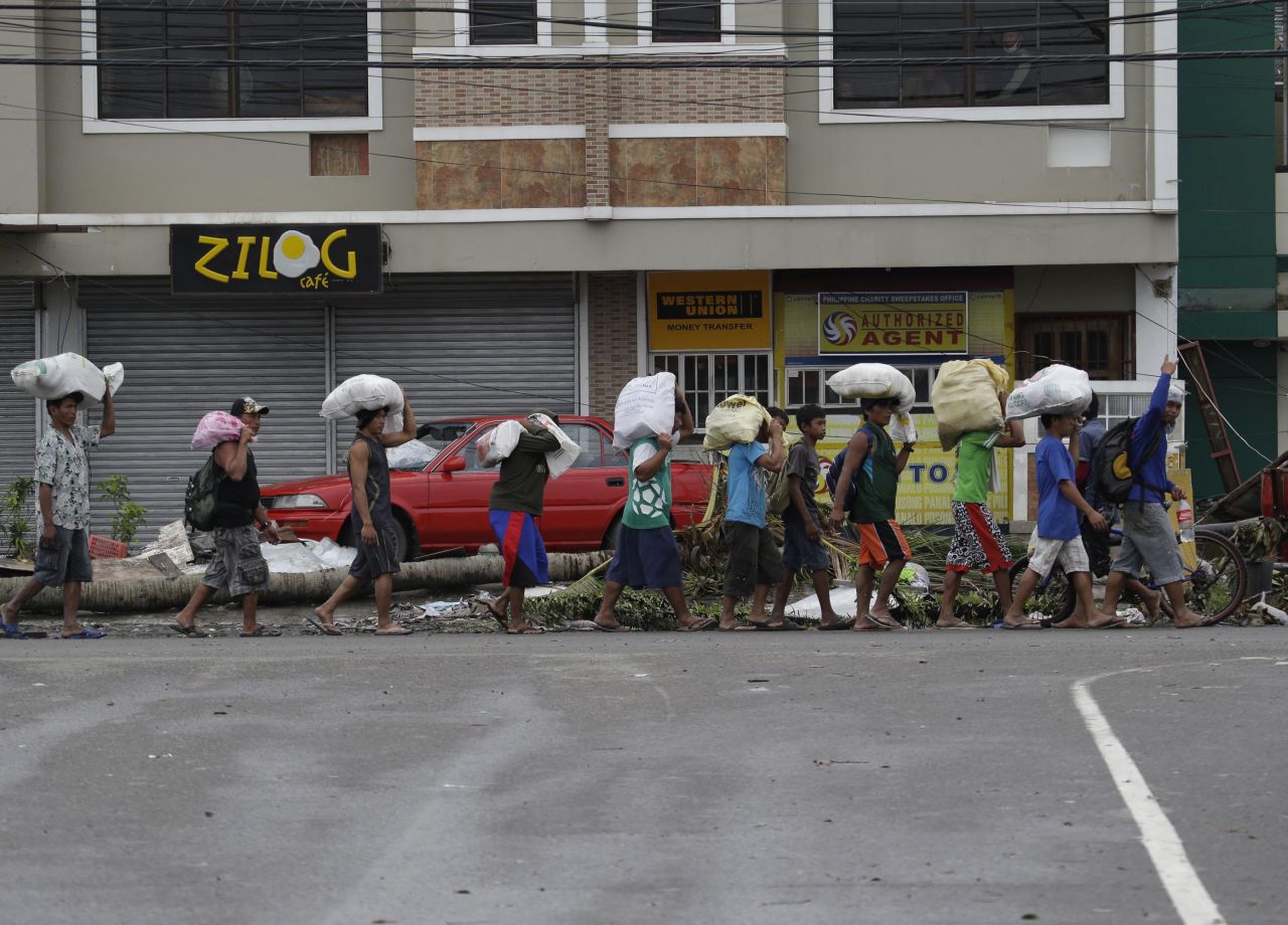 People carry sacks of goods November 12 in Tacloban.