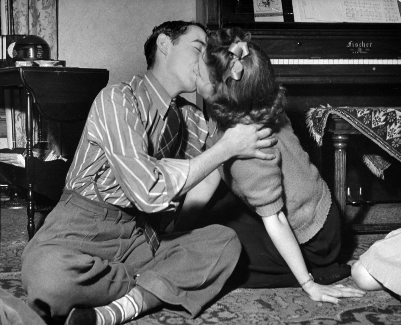 Teens kiss during a game of spin the bottle at a party in 1942.