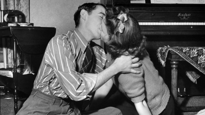 A couple of teens kiss during a game of spin the bottle at a party in 1942.