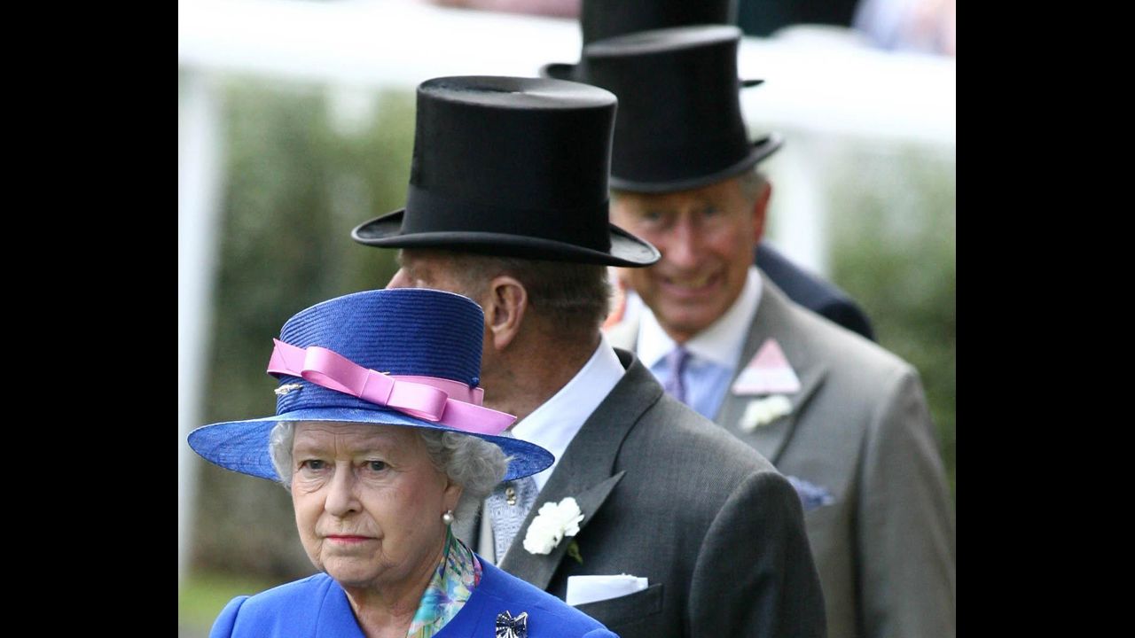 Charles, out of focus, smiles at the camera while following his mother and his father, Prince Phillip, Duke of Edinburgh. for the first day of the royal meeting at the new state-of-the-art course at Ascot in Berkshire in June 2006. 