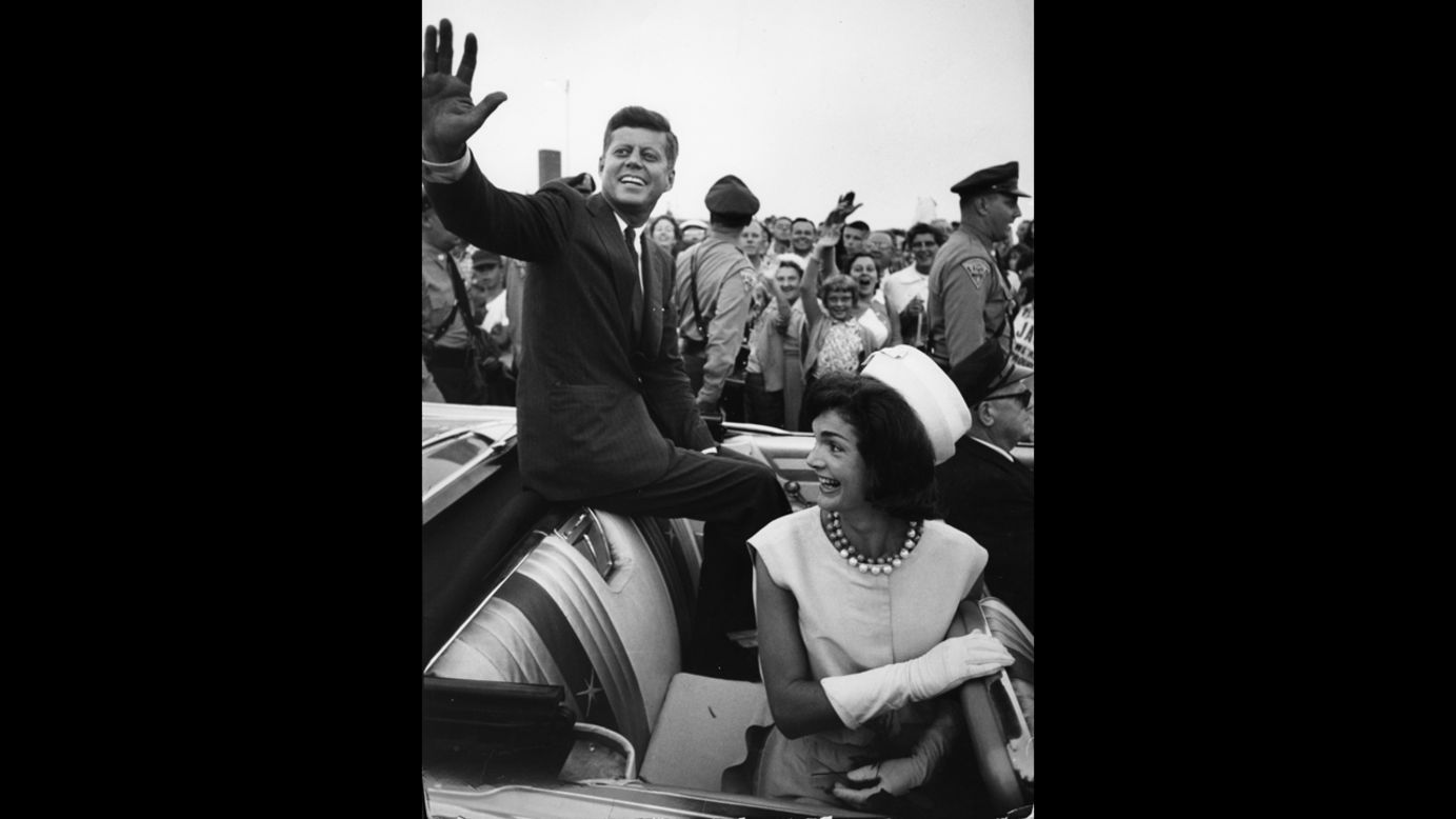 Shortly after his acceptance of the Democratic Party nomination for president, Kennedy and his wife smile and wave from the back of an open-top car in Massachusetts in July 1960.