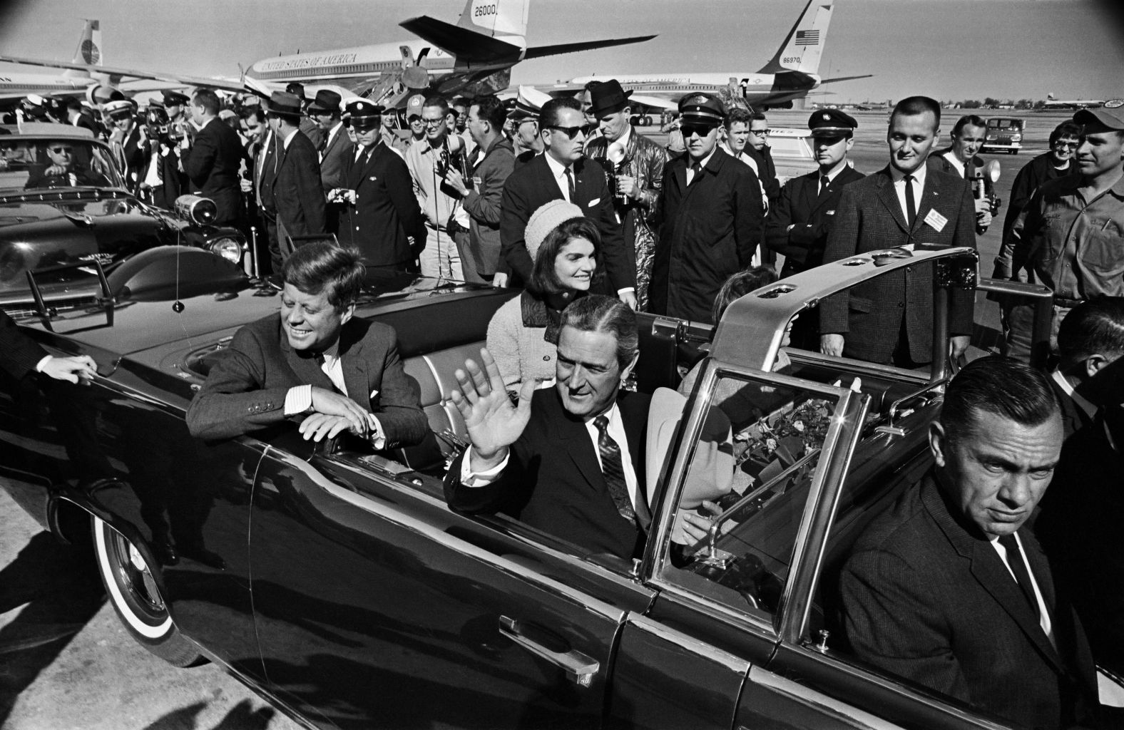 Texas Gov. John B. Connally Jr. waves to the crowd at Love Field as the Kennedys leave for a 10-mile tour of Dallas. The president asked about the weather earlier in the day and opted not to have a top on the limousine. 