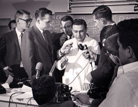 Before 1 p.m., Dr. Tom Shires, with Parkland public relations director Steve Landregan, rear, describes the President's wounds to the press. Four doctors worked on the stricken Kennedy in the emergency room.