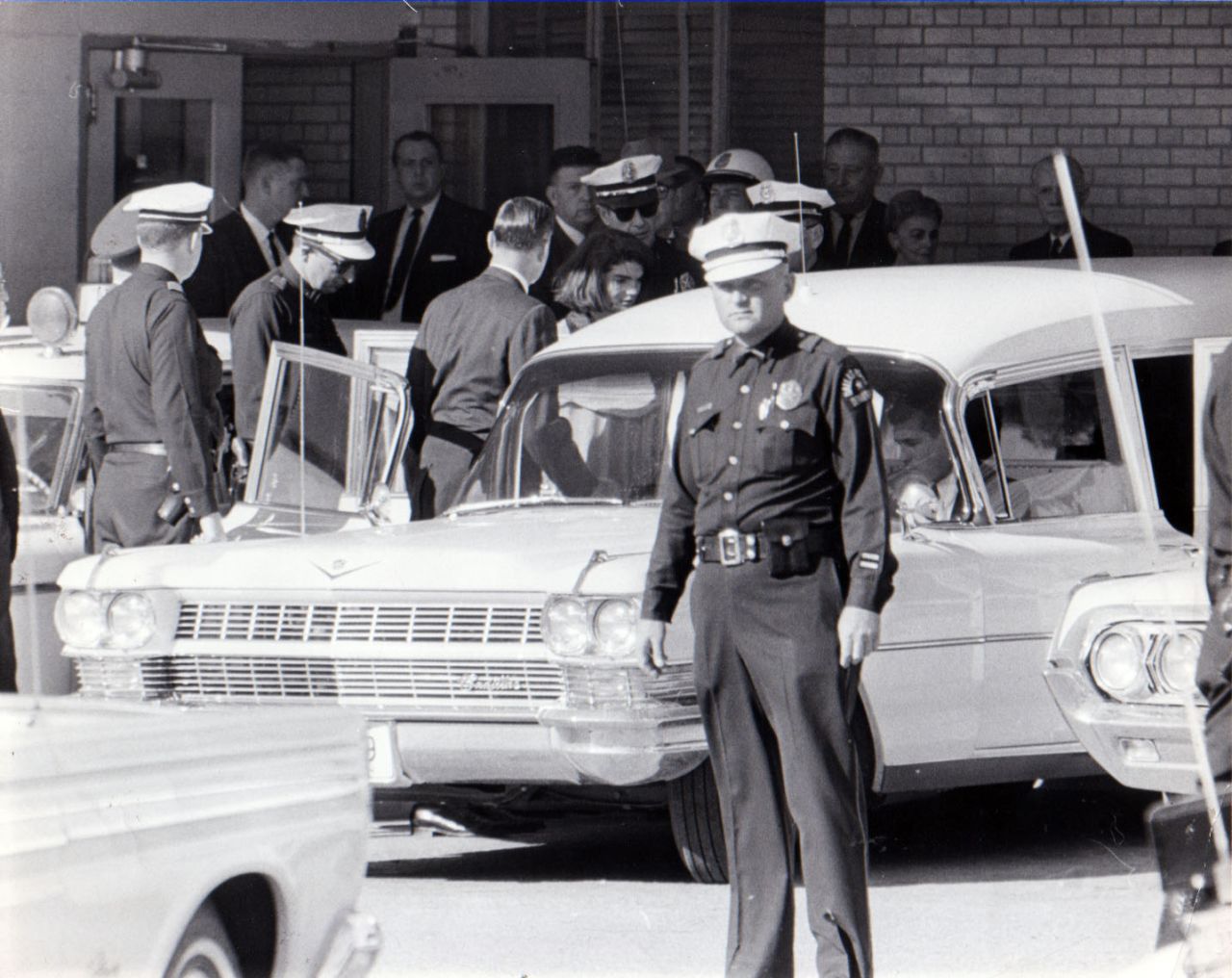 After 2 p.m., Jacqueline Kennedy leaves Parkland Hospital with her slain husband's body. She would ride in the back with the bronze casket. "I had a feeling that if somebody had literally fired a pistol in front of her face that she would just have blinked," said Dallas Police Officer James Jennings, who helped put the casket in the hearse. 