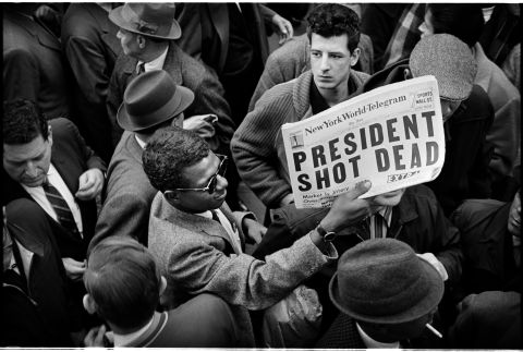 A man holds up a copy of the New York World-Telegram featuring the news of the assassination. Major television and radio networks devote continuous news coverage to the events of the day, canceling all entertainment and all commercials. Many theaters, stores and businesses, including stock exchanges and government offices, are closed.