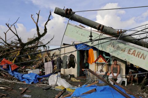 A man sits in front of his destroyed business November 13 in Tacloban.