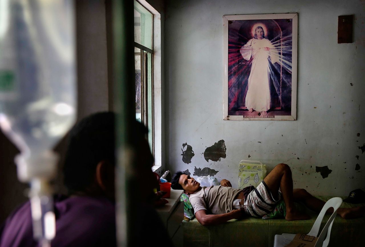 An injured man in Tacloban rests beneath a picture of Jesus Christ on November 13.