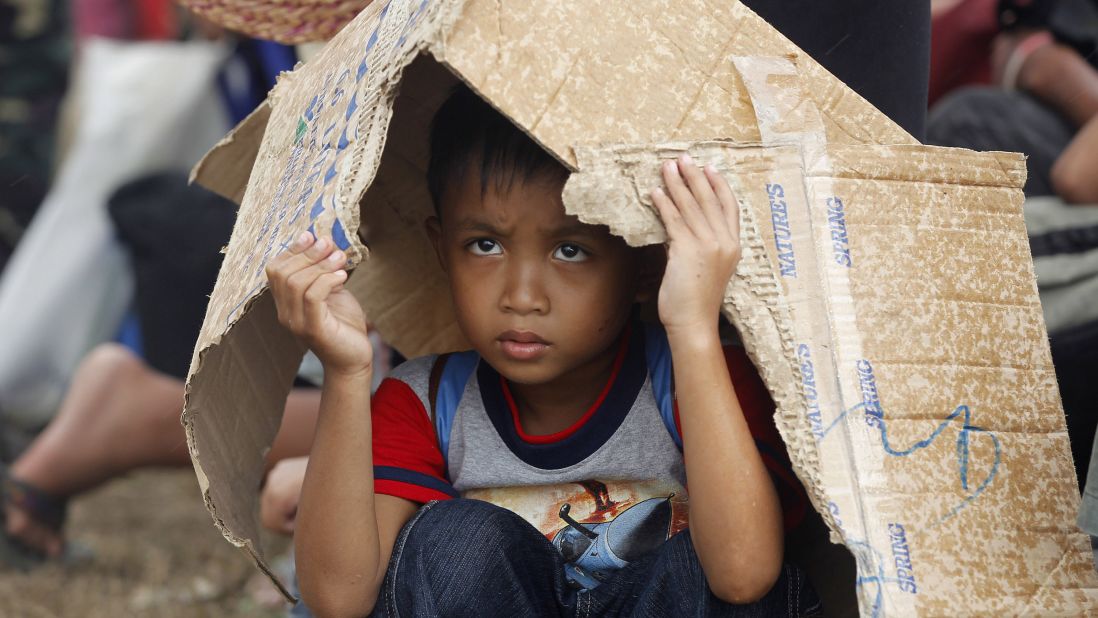 A boy takes cover from rain while waiting for an evacuation flight from Tacloban's airport November 14.