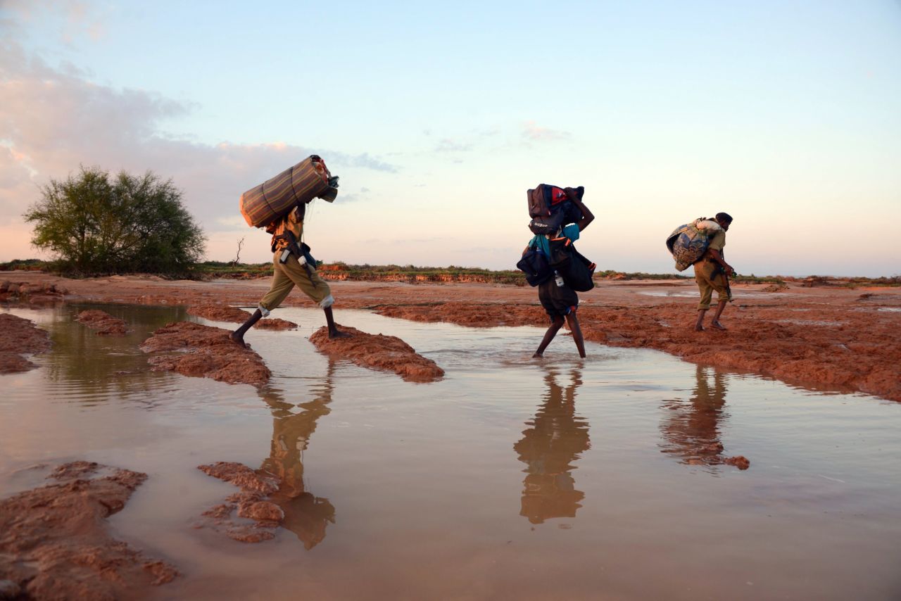 La gente camina con sus pertenencias en el área alrededor de Sinujiif  mientras son evacuados  el 14 de noviembre de 2013, tras una feroz tormenta y días de fuertes inundaciones en la región de Puntland, al noreste de Somalia. Durante los últimos seis años, Somalia ha ocupado uno de los diez primeros lugares en el índice de riesgo político de Maplecroft.<br />