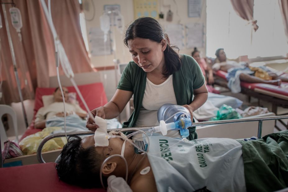 A typhoon survivor keeps her husband alive by manually pumping air into his lungs after his leg was amputated at a Tacloban hospital November 15. The hospital has been operating without power since the typhoon.