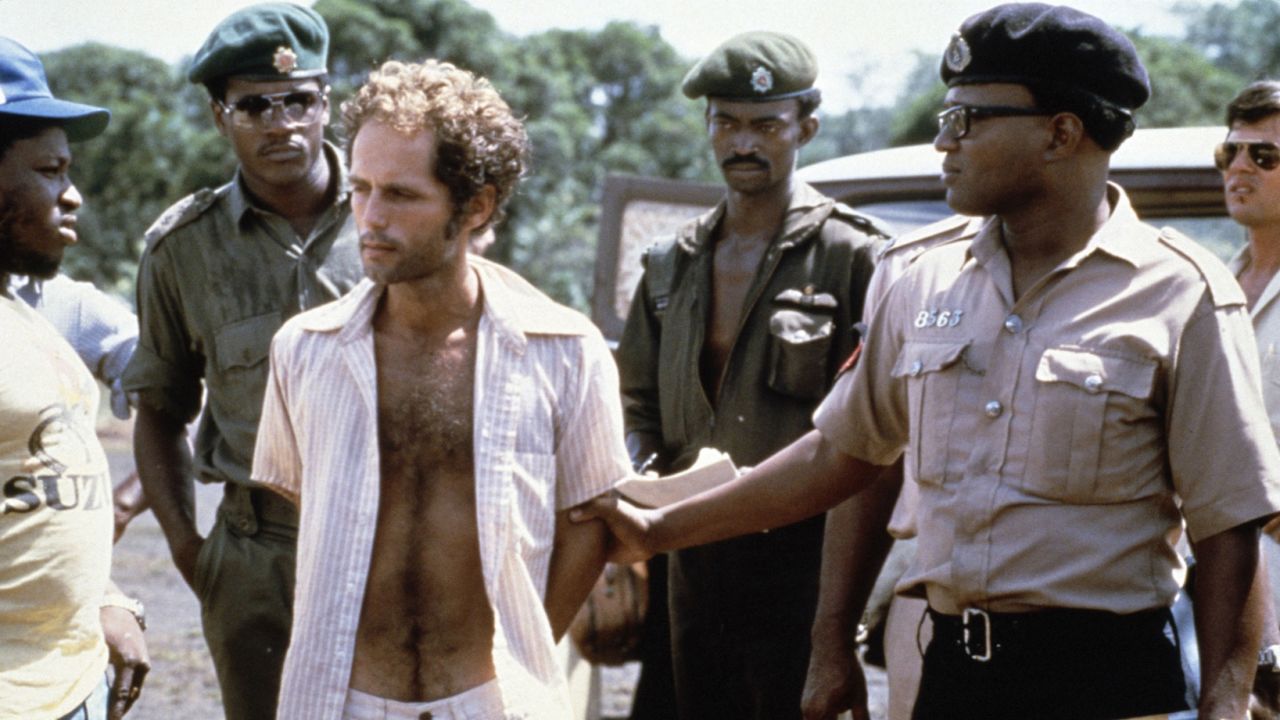 People's Temple follower Larry Layton, center, stands with police following his arrest in connection with the shooting at the remote Guyana airstrip. Layton was convicted in 1986 by a federal jury in San Francisco of conspiring in Ryan's murder and aiding and abetting in the attempted murder of Richard Dwyer, a U.S. diplomat wounded in the attack. 