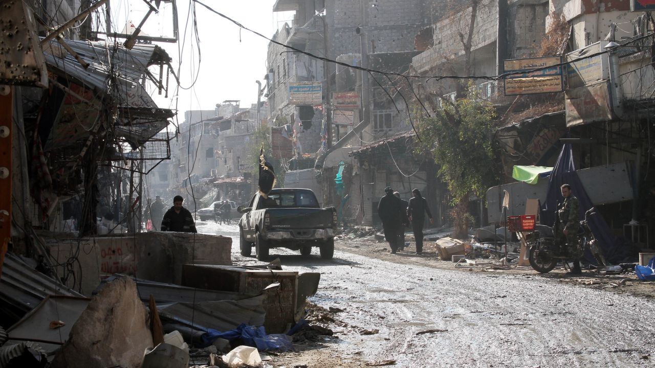 People walk on a street between destroyed buildings in the town of Hejeira in the countryside of Damascus on November 13.
