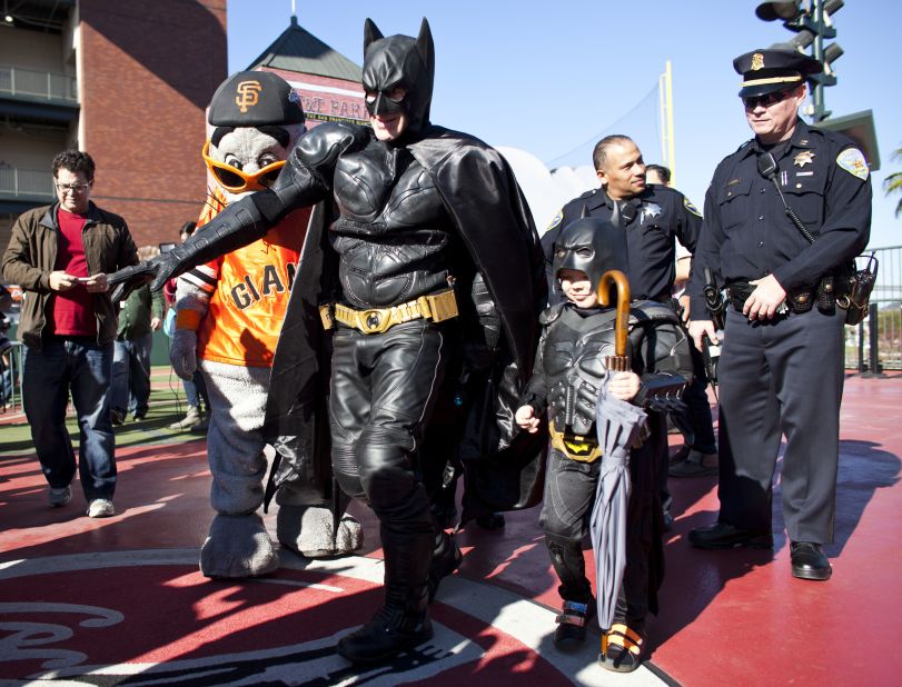 Miles, as Batkid, walks with Batman after releasing San Francisco Giants mascot Lou Seal from the Penguin as part of a Make-A-Wish foundation fulfillment at AT&T Park in November 2013.