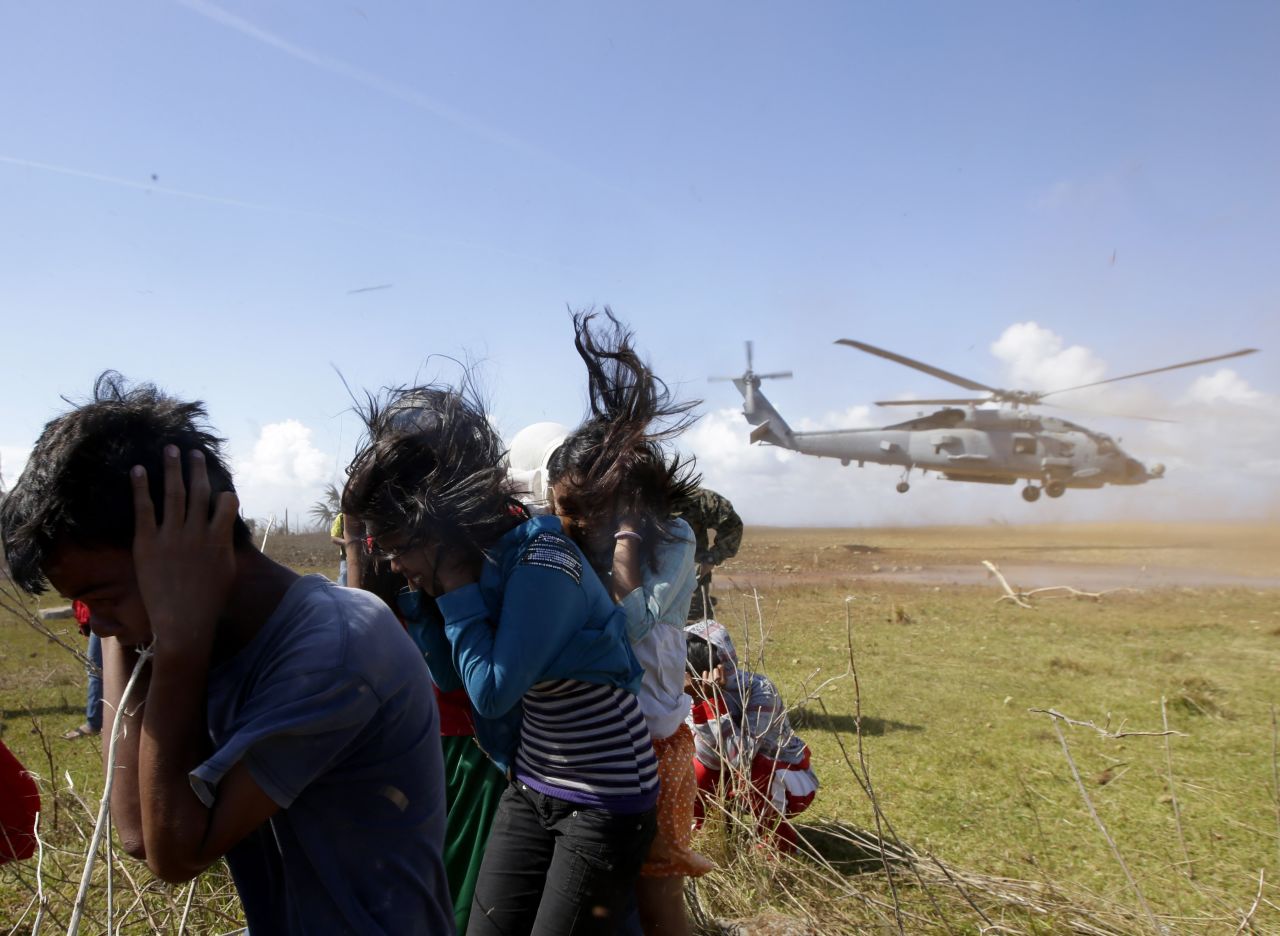 Trapped residents protect themselves from dust as a U.S. Navy helicopter takes off Saturday, November 16, on the Philippines' Manicani Island.