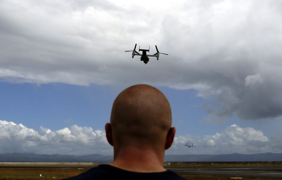 A U.S. aircraft flies above the Tacloban airport as a U.S. Marine watches November 16. 