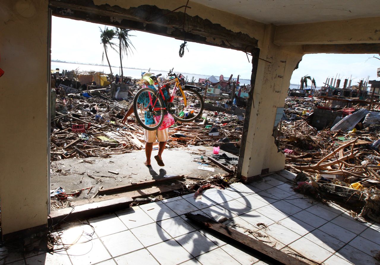 A man carries a bicycle as he walks through the ruins of a Tacloban building November 16.