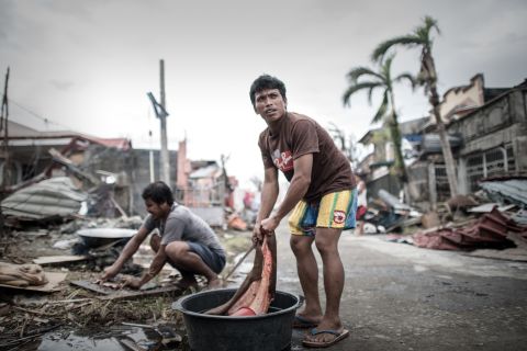 A man in Tanauan cleans meat after slaughtering his only cow that survived the typhoon.