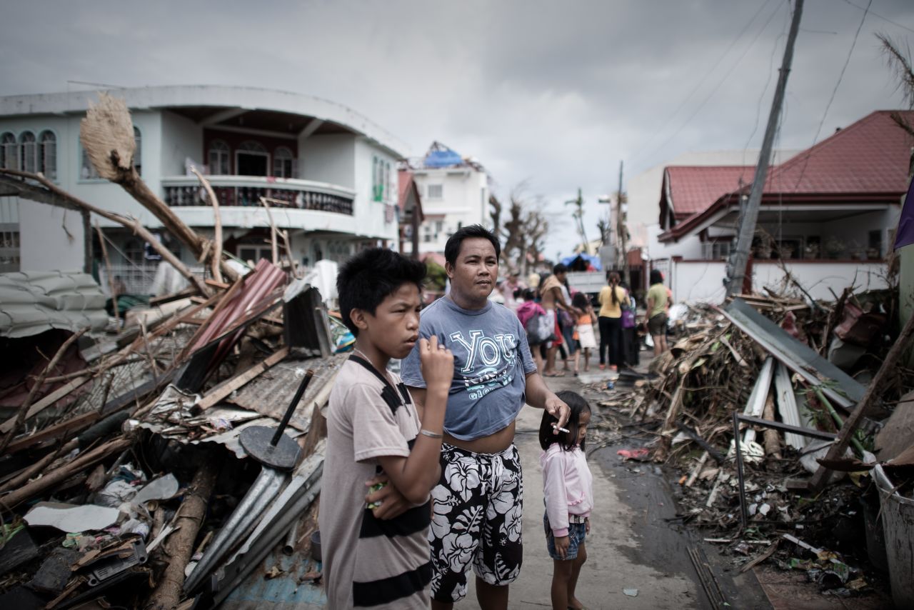 Survivors of the typhoon stand in a Tanauan street partially blocked by debris November 16.