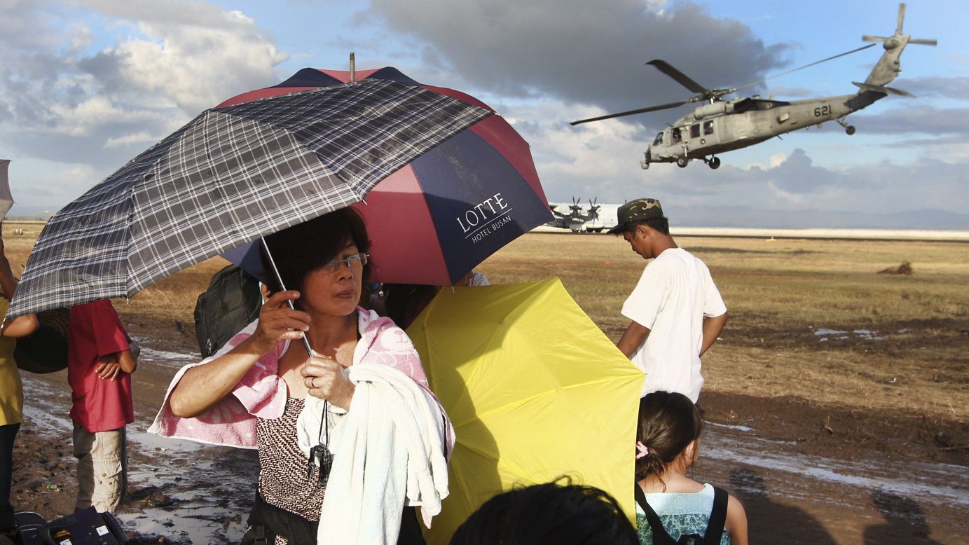 Typhoon survivors wait for an evacuation flight as a U.S. Navy helicopter takes off at the Tacloban airport Sunday, November 17.