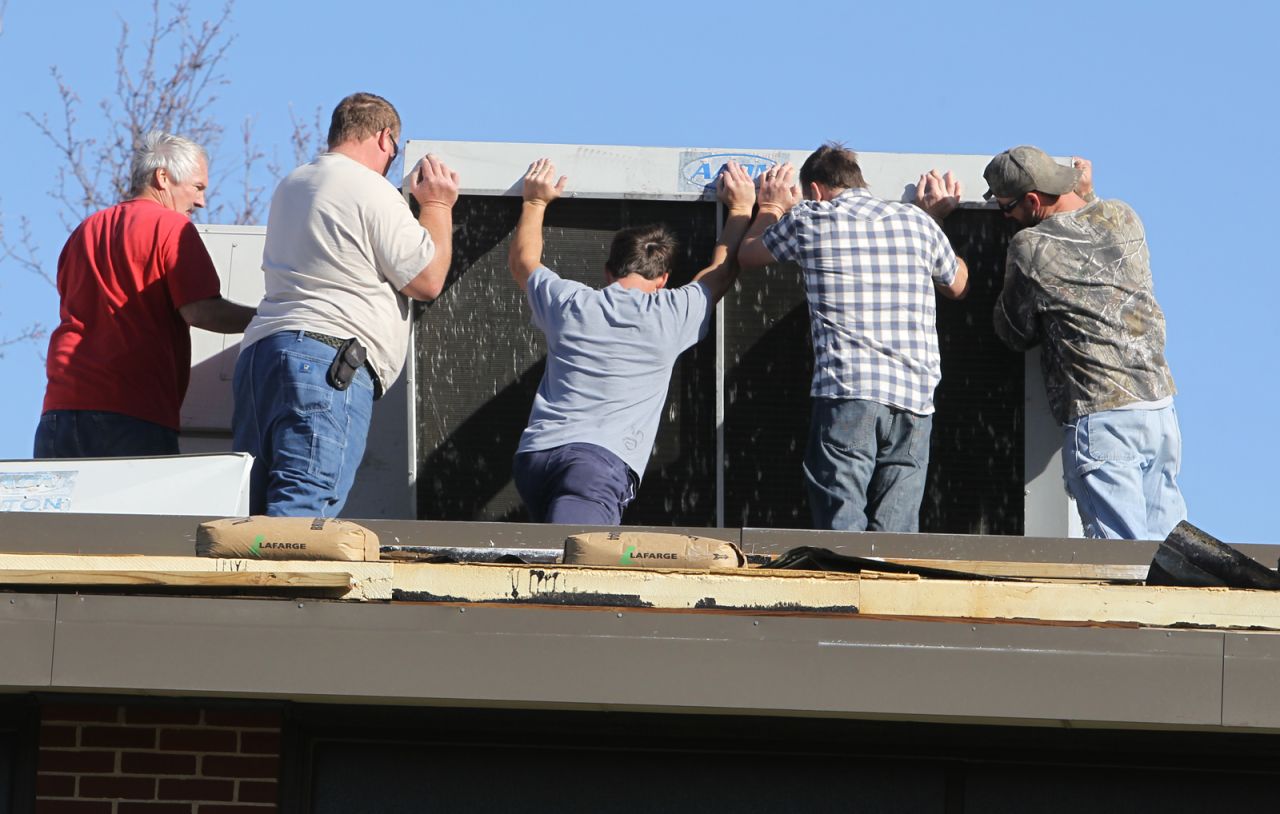 Volunteers try to reposition the HVAC unit on top of Heritage Primary Elementary School in Wentzville, Missouri, on November 17. Board members, staff and teachers came to the school to help with the cleanup after a storm tore off parts of the roof. Wentzville is about 40 miles west of St. Louis.