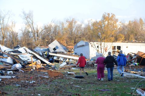 An elderly woman is escorted through tornado debris in Brookport, Illinois, on November 17.