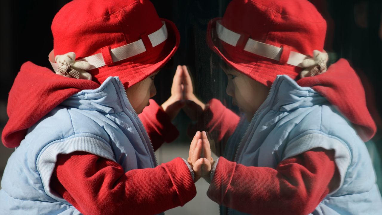 A child looks at his reflection in a window in Beijing on November 17, 2013. On November 15 China's Communist rulers announced an easing of the country's controversial one-child policy as part of a raft of sweeping pledges including the abolition of its 're-education' labour camps and loosening controls on the economy.