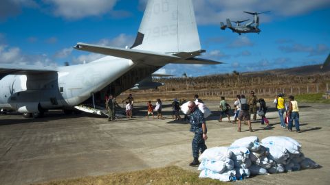 Filipinos board an HC-130 Hercules airplane as U.S. sailors carry relief supplies November 17 in Guiuan.