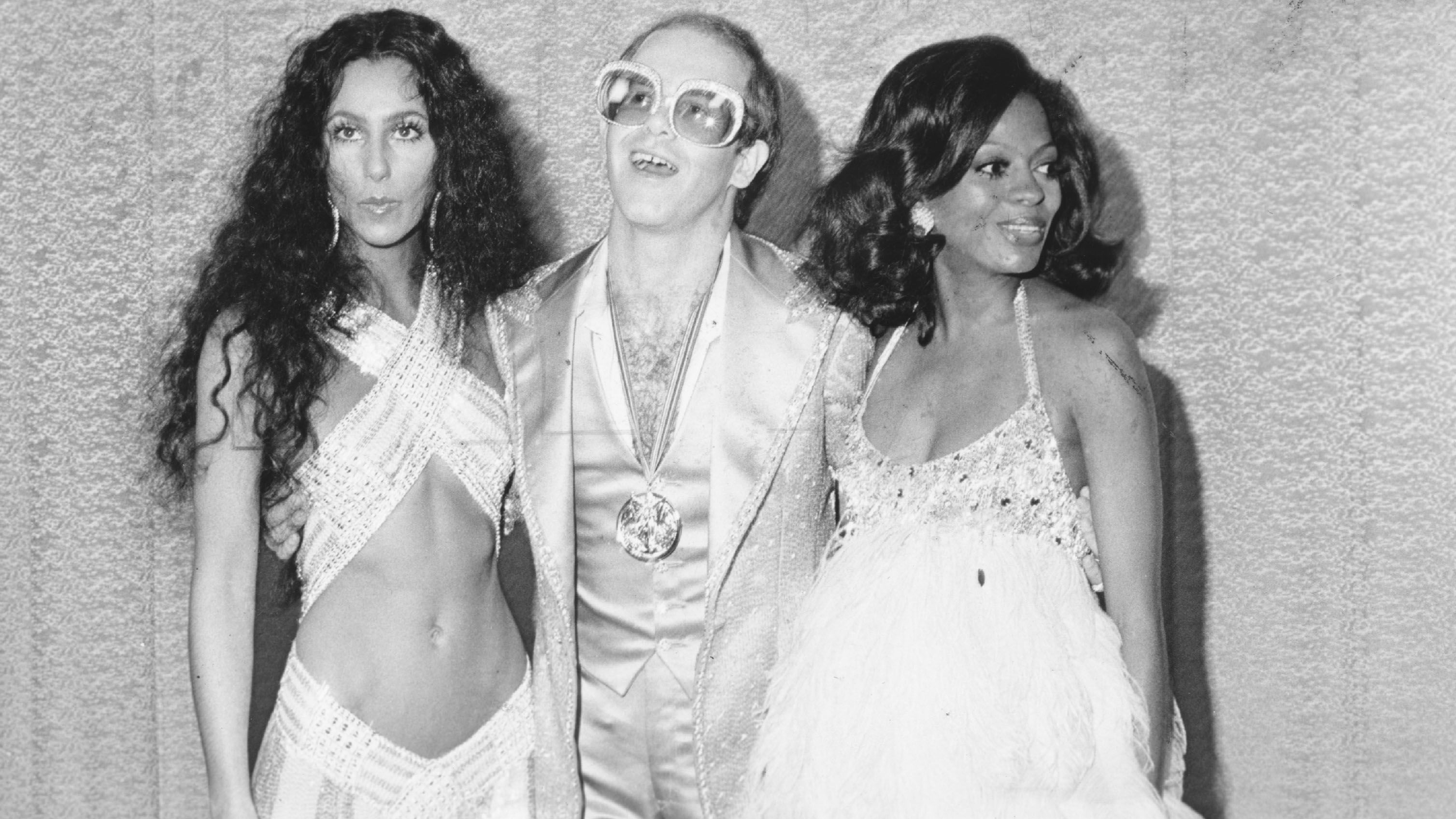 John poses for a photo with Cher and Diana Ross in the mid-1970s.