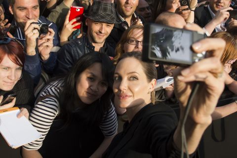 Actress Angelina Jolie takes a photo of herself with a fan's camera at the Paris premiere of "World War Z."
