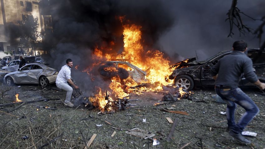 Lebanese men run to remove dead bodies from burned cars, at the scene where two explosions have struck near the Iranian Embassy killing several, in Beirut, Lebanon, Tuesday Nov. 19, 2013. The blasts in south Beirut's neighborhood of Janah also caused extensive damage on the nearby buildings and the Iranian mission. The area is a stronghold of the militant Hezbollah group, which is a main ally of Syrian President Bashar Assad in the civil war next door. It's not clear if the blasts are related to Syria's civil war. (AP Photo/Hussein Malla)